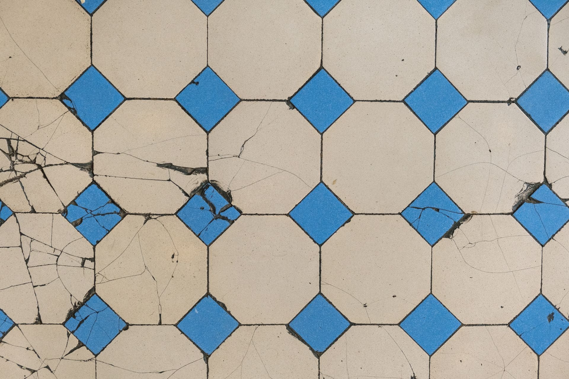 Worn and cracked tile flooring in an older building, ready for removal