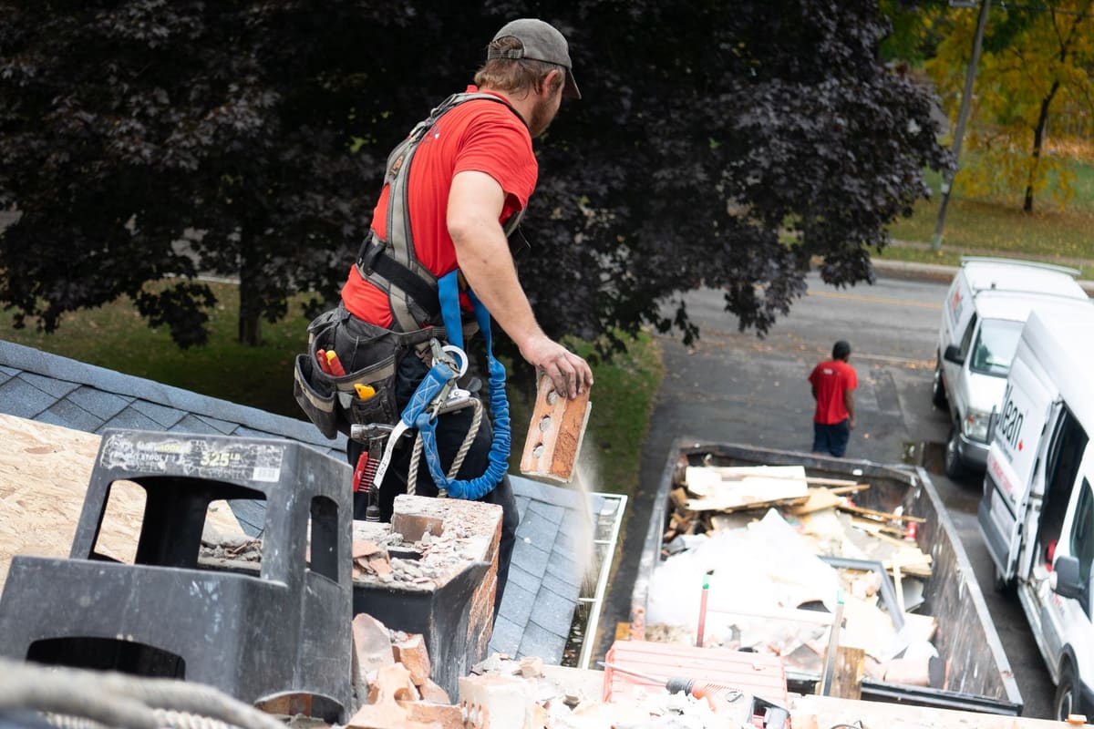 Worker loading demolition debris into a dumpster for disposal
