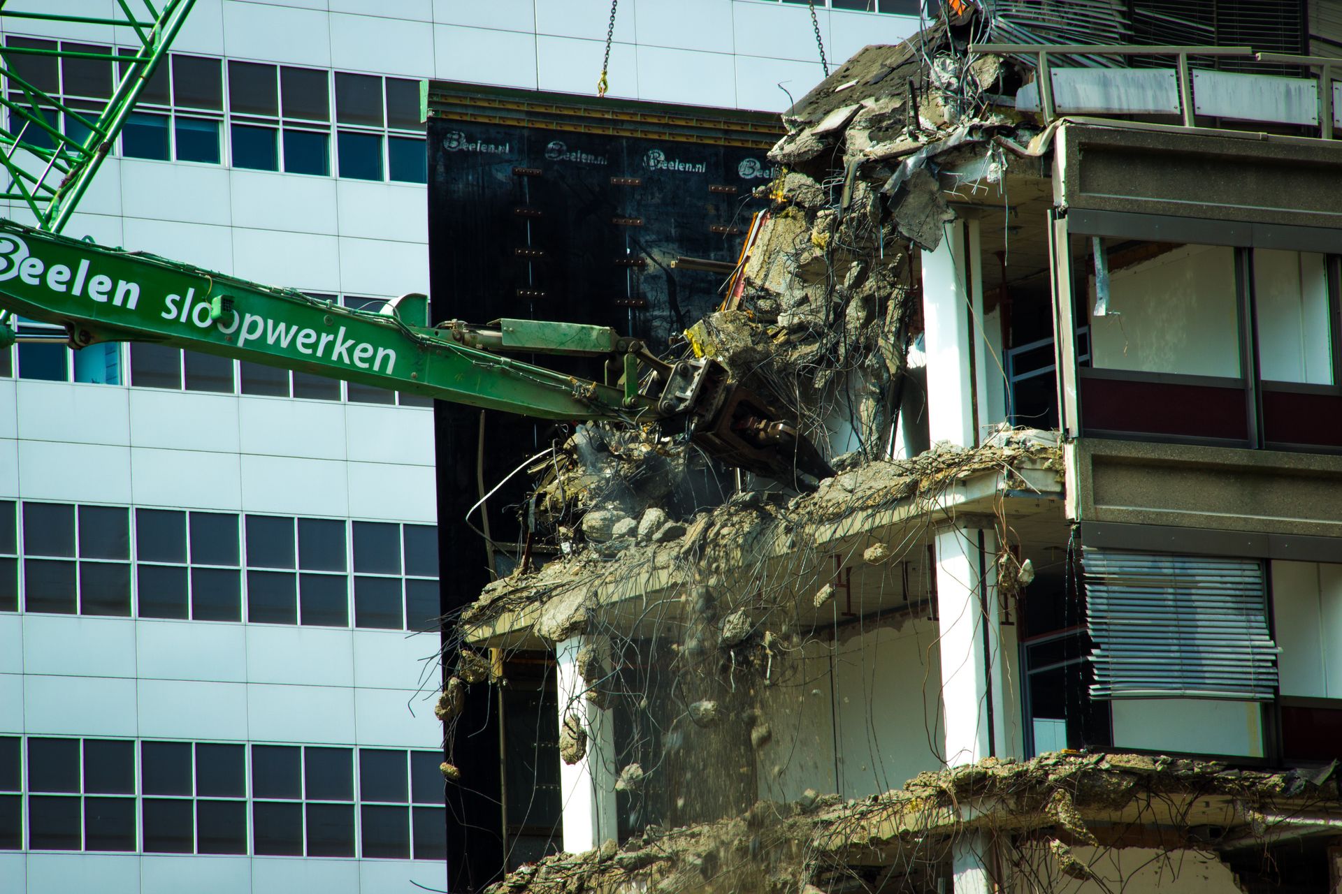 High-reach excavator using shear attachment to remove reinforced concrete floors from a commercial building structure.