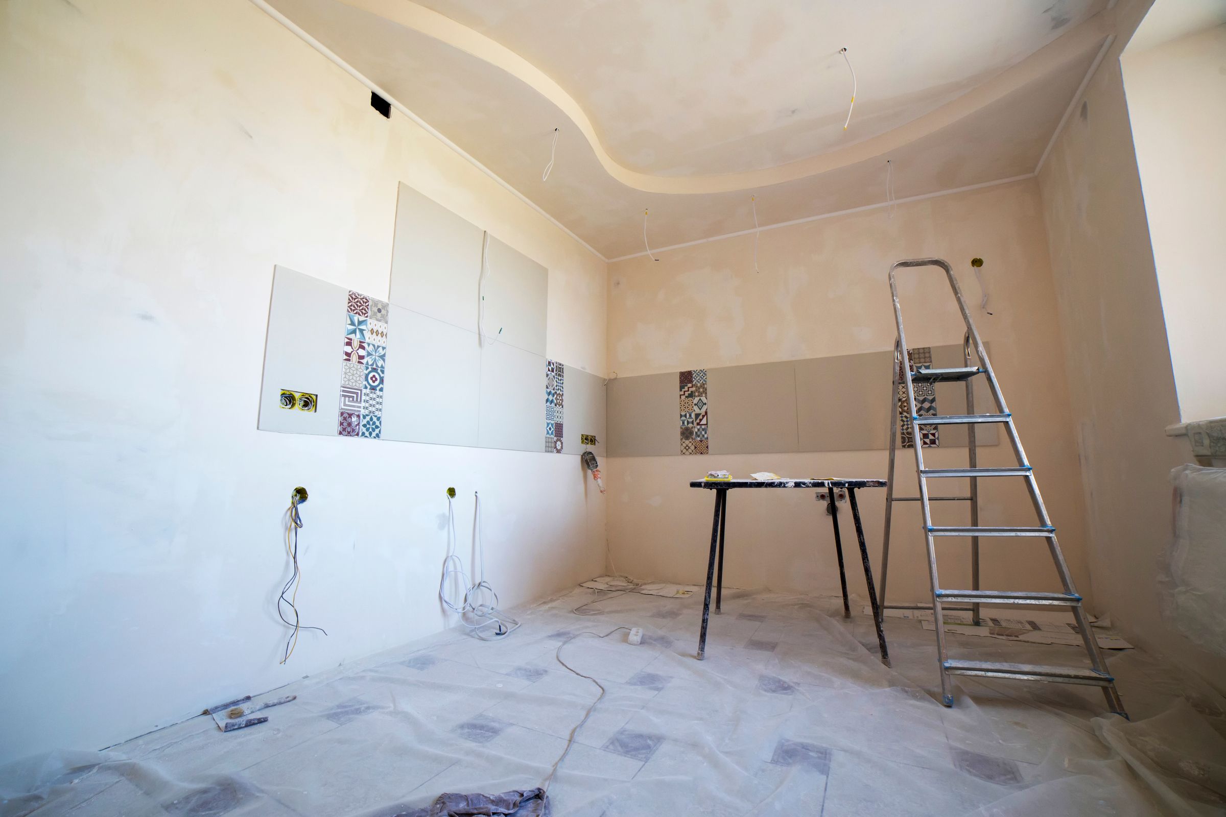 Room mid-renovation with tile flooring and tools before the old floor is torn out